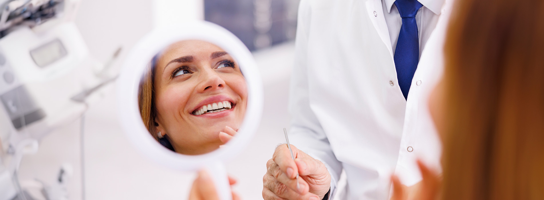 The image shows a group of people, possibly professionals given their attire and the setting that appears to be an office or professional environment. They are gathered around a table with a laptop on it, engaged in what seems to be a discussion or meeting.